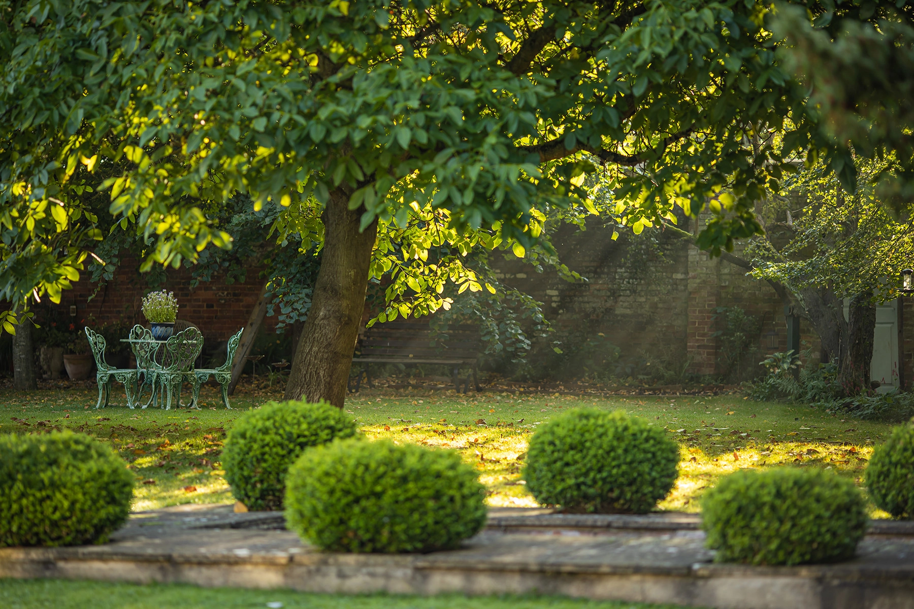 Outdoor entertaining space integrated into elegant Cotswolds kitchen garden design by Nicholsons.