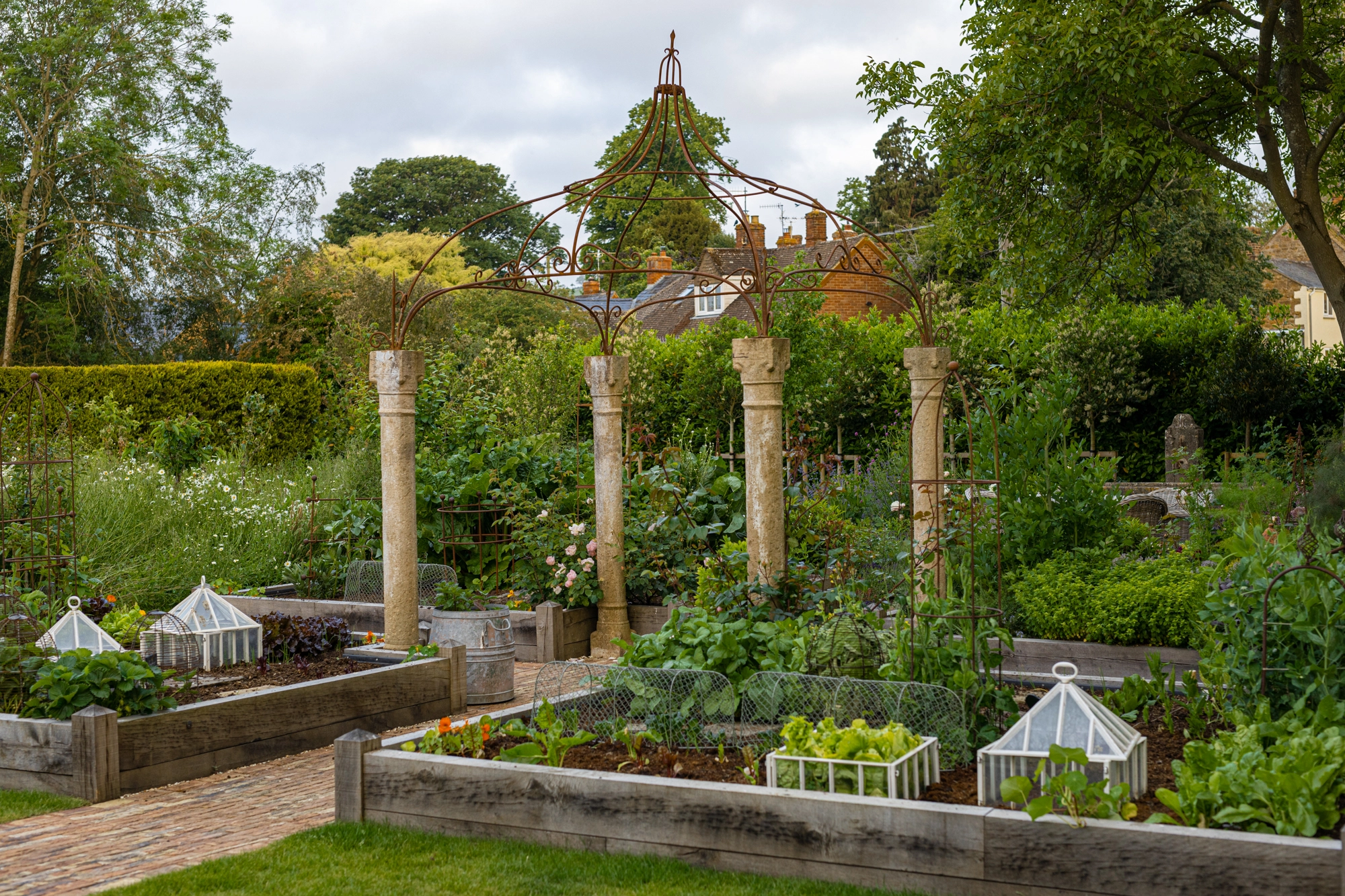 Cotswolds kitchen garden design with raised beds and colourful borders beside a period home